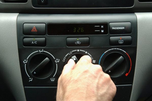 Foto de um painel de ar condicionado automotivo mostrando homem girando botão de regulagem de temperatudo do ar dentro do veículo para a página Ar Condicionado Automotivo da Hot Tape em Vitória / ES