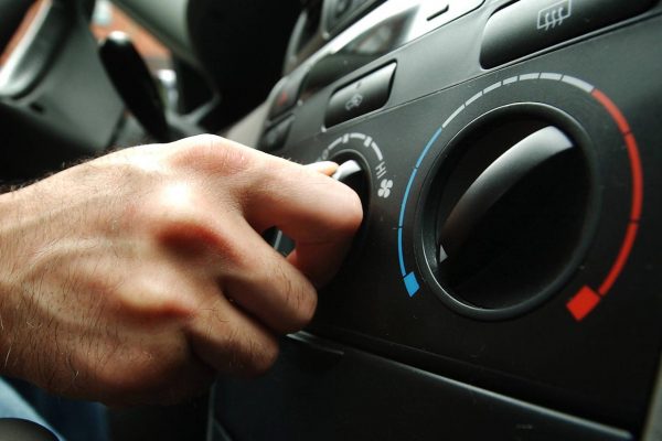 Foto de um painel de ar condicionado automotivo mostrando homem girando botão de regulagem de temperatudo do ar dentro do veículo para a página Ar Condicionado Automotivo da Hot Tape em Vitória / ES